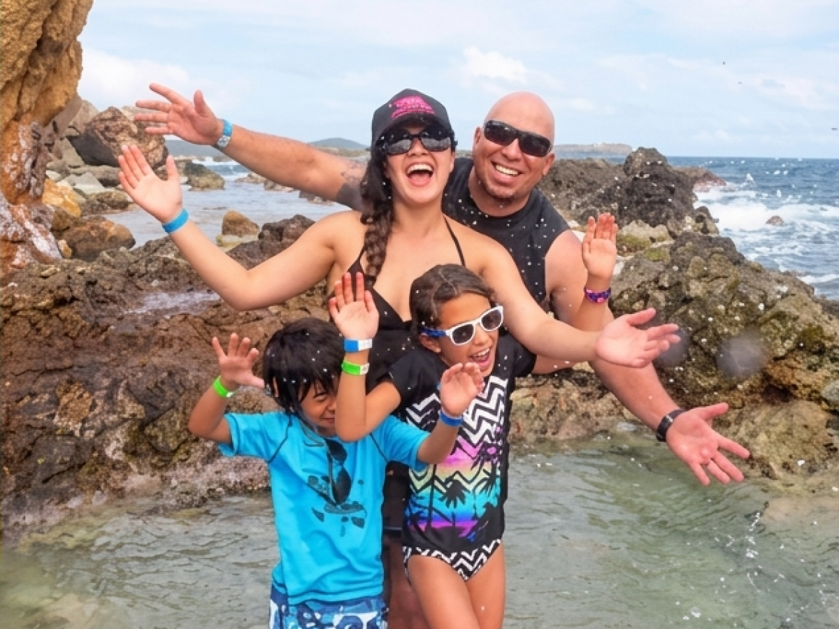 A family of four happily posing on a rocky beach.
