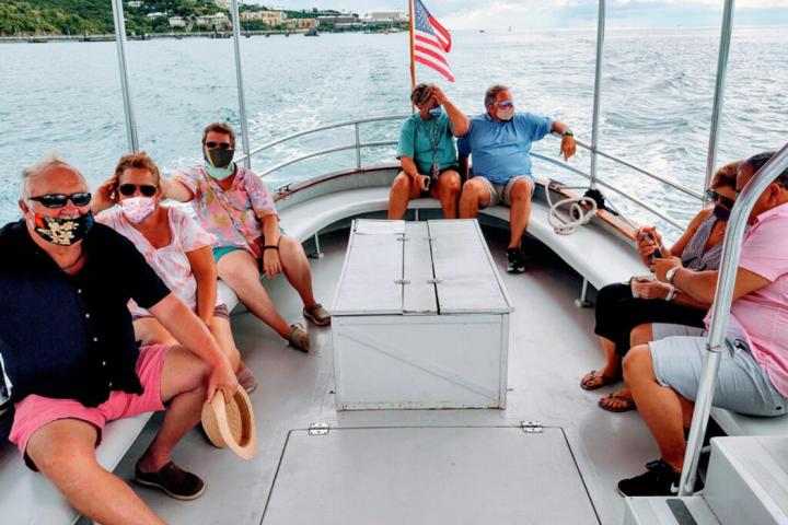 Group of people wearing masks on a boat with a U.S. flag.