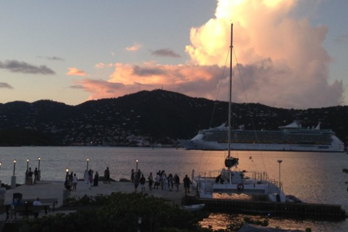 Sunset at a dock with boat and distant cruise ship.