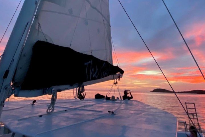 Sailboat on water at sunset with colorful sky.