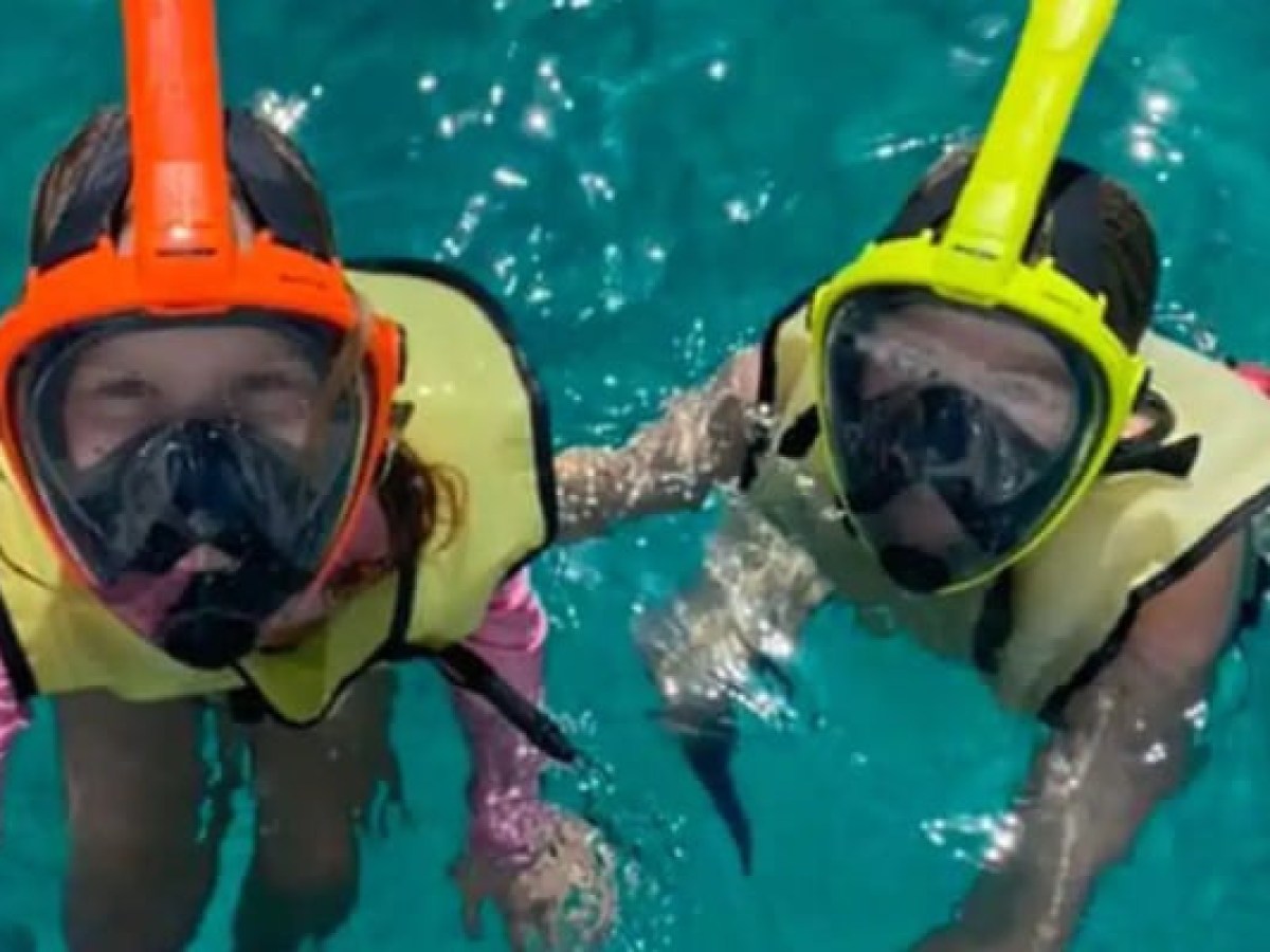 Two people snorkeling in clear blue water, wearing vests and snorkels.