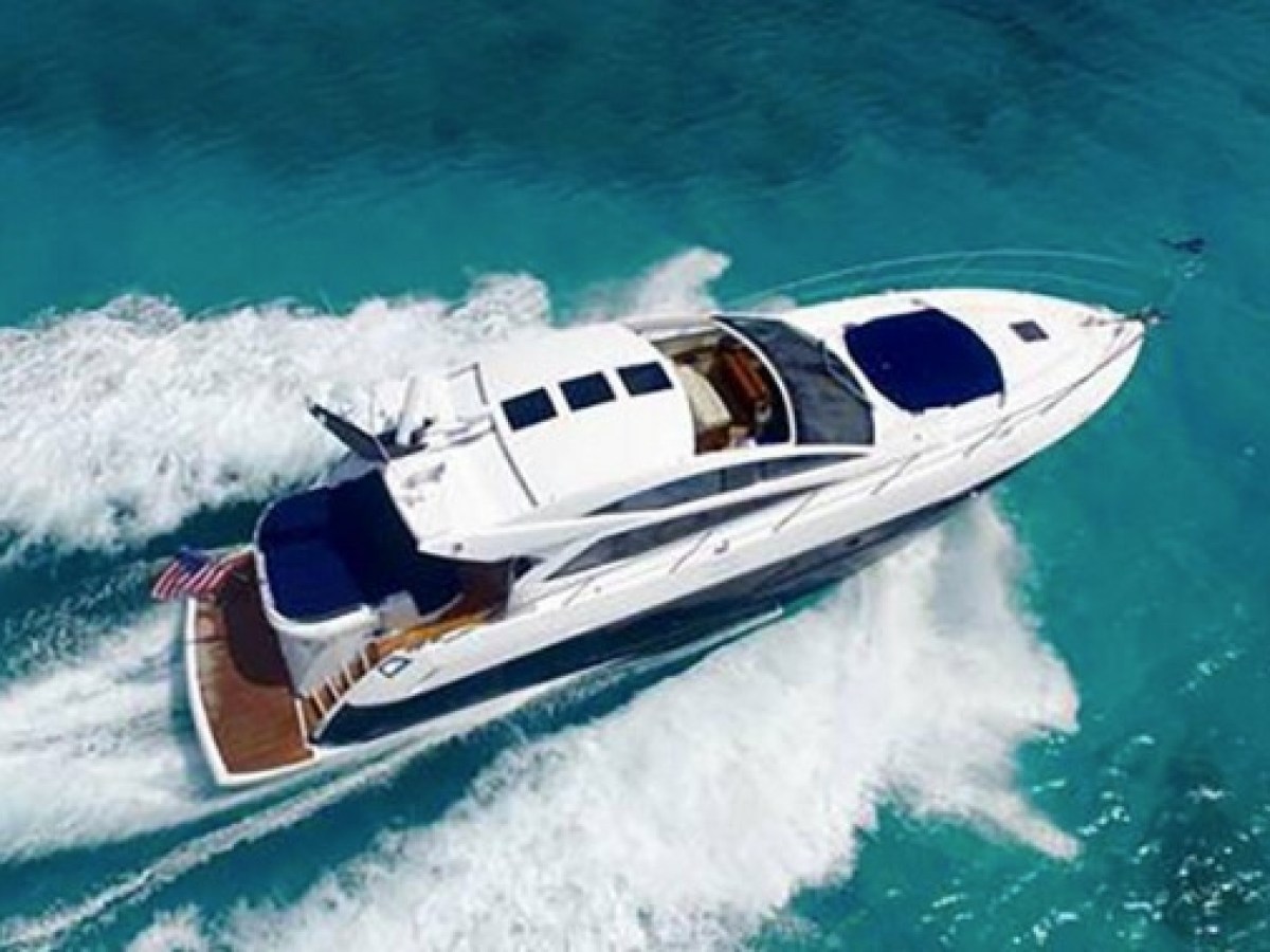 Aerial view of a white yacht cruising on clear blue water.