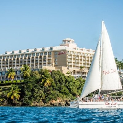 Sailboat in front of a large hotel by the ocean.