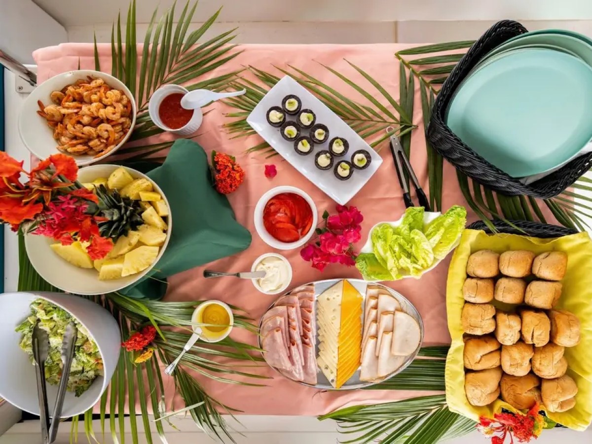 Assorted tropical snacks and bread on a table with decorative leaves and flowers.