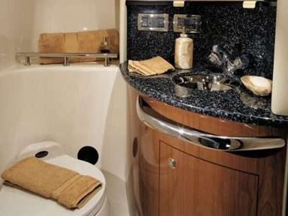 Compact bathroom with toilet, sink, and black granite countertop.