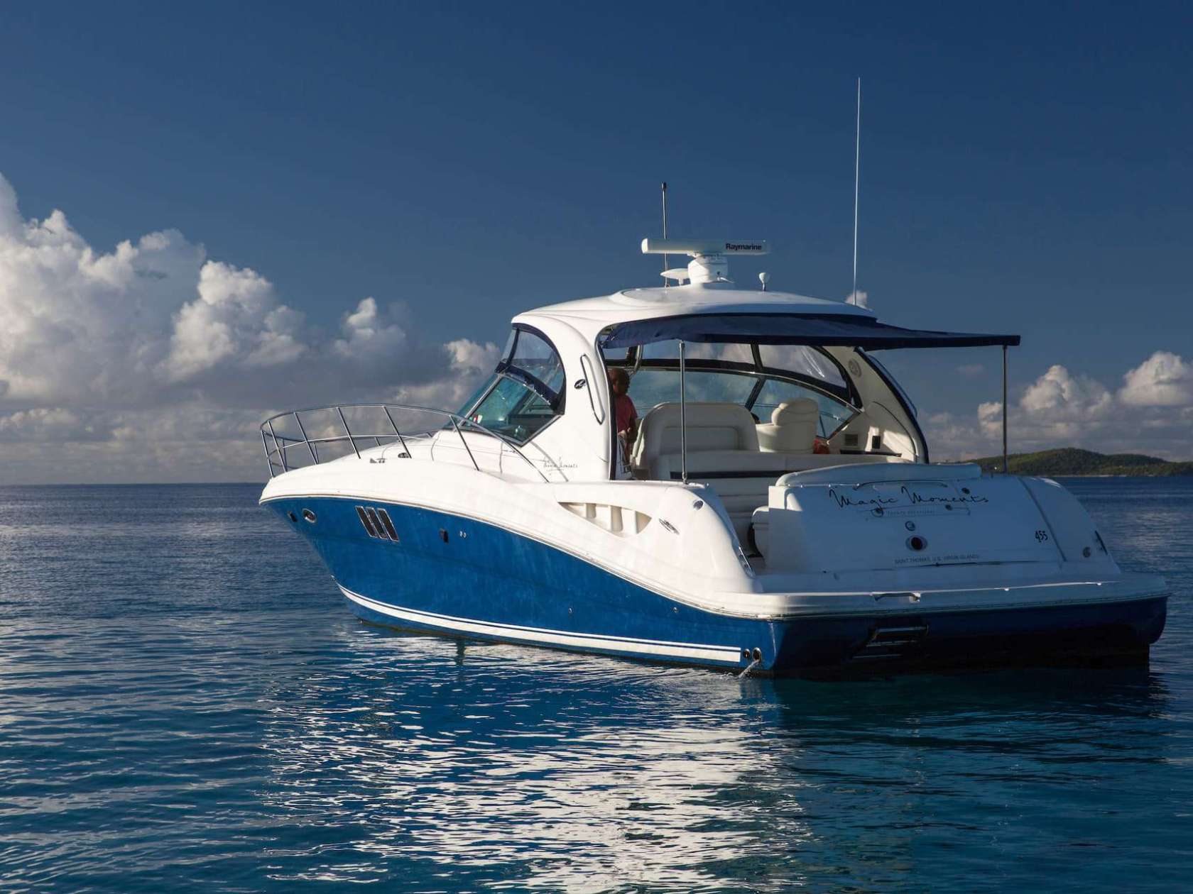 Blue and white motorboat floating on calm water under a clear sky.