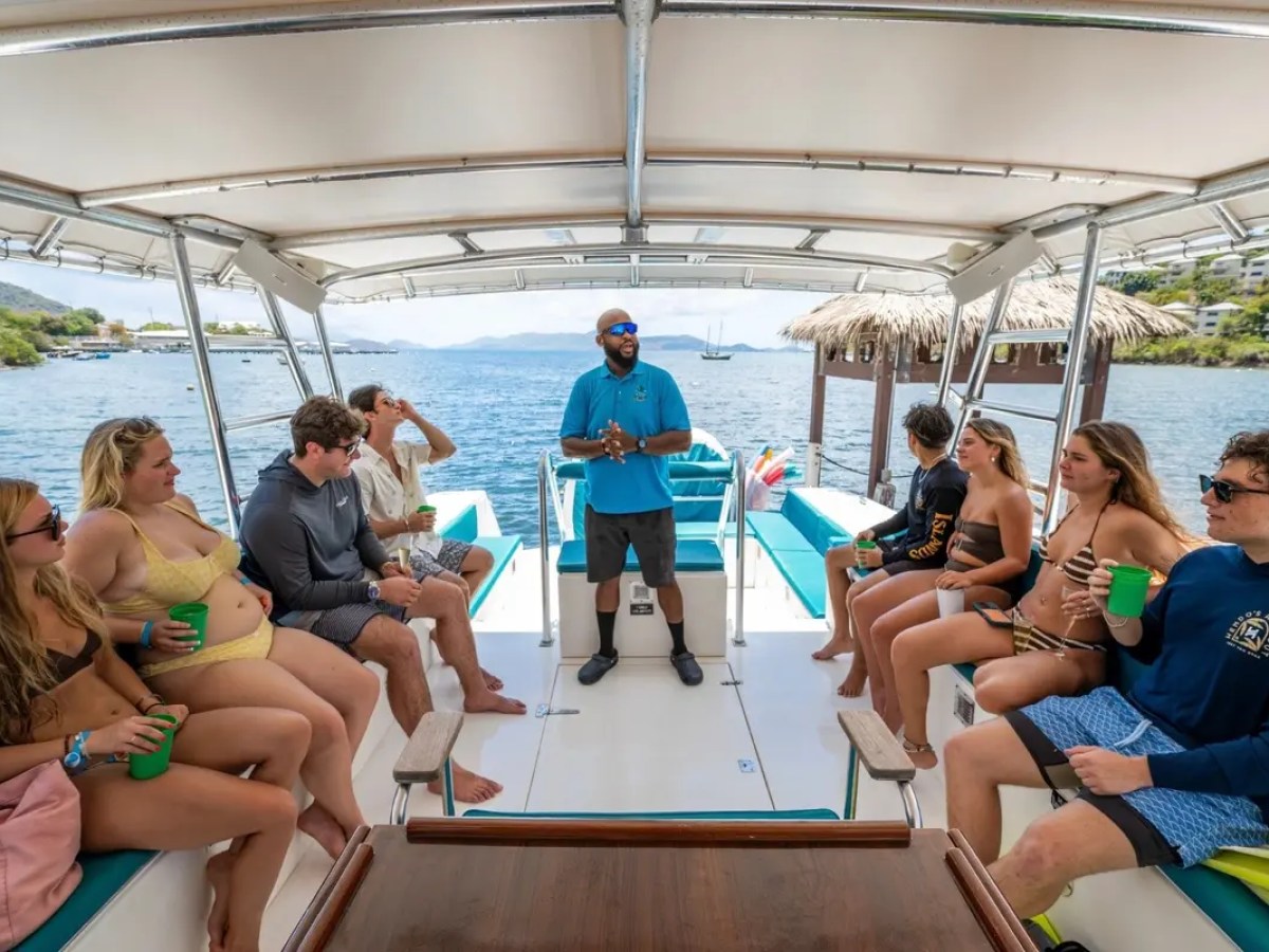 Group of people sitting on a boat, enjoying drinks.
