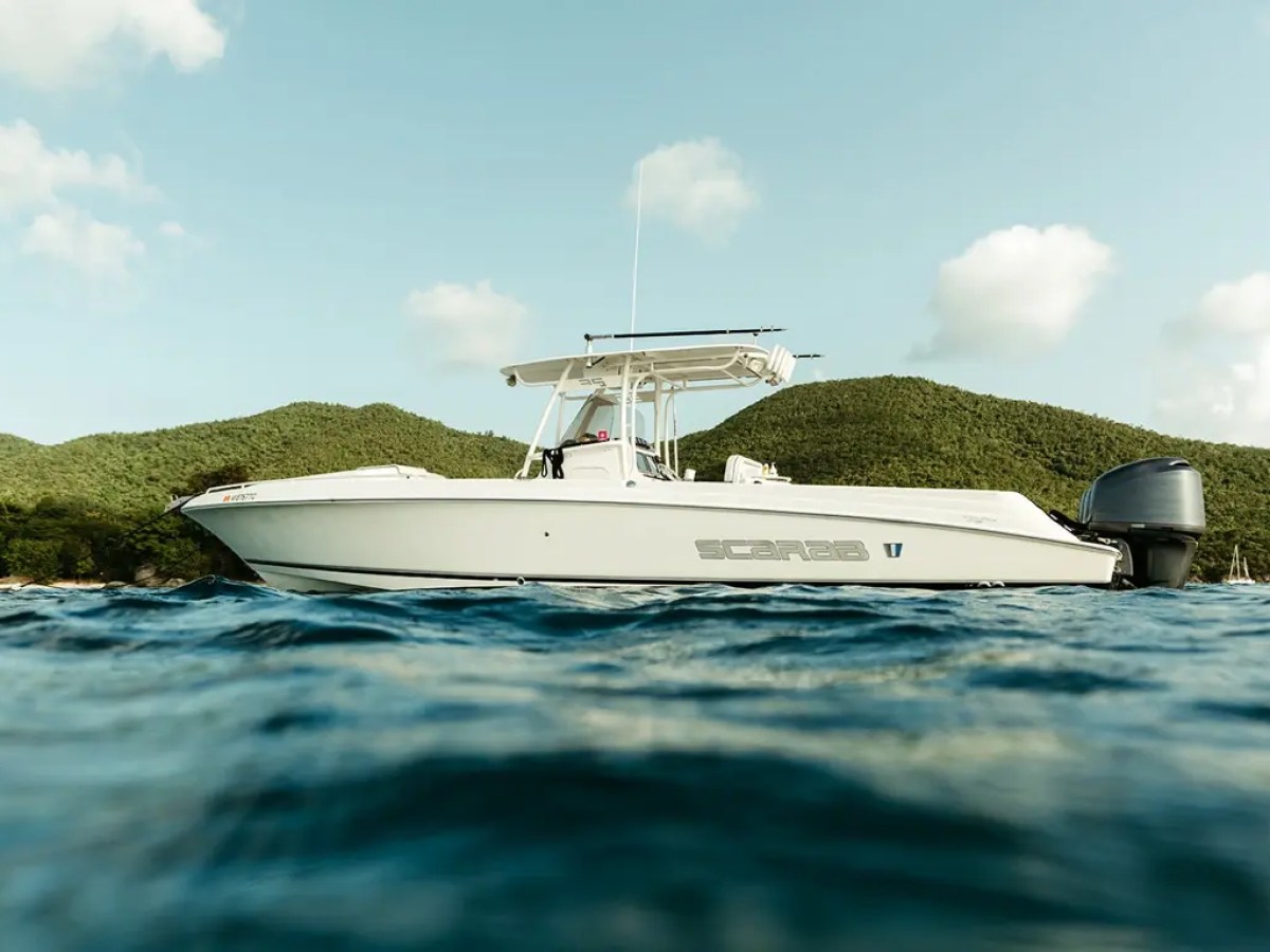 White motorboat on the water with green hills in the background.